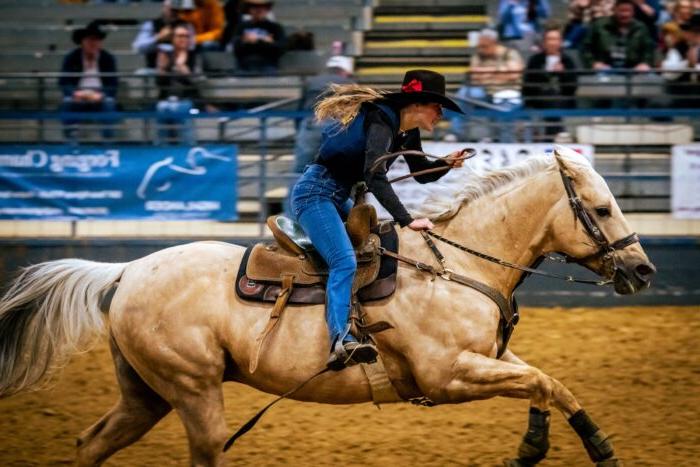 A cowgirl rides a horse during a rodeo competition.